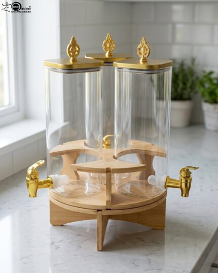 Triple glass beverage dispenser set featuring gold spigots, gold decorative lids, and a wooden rotating stand on a kitchen countertop.