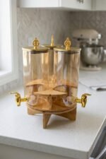 3-piece amber shaded glass beverage dispenser set with gold spigots on a wooden stand