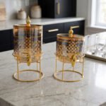 Luxury amber glass beverage dispenser with intricate blue pattern on a decorative gold metal stand