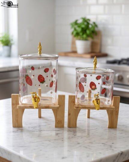 Two strawberry pattern glass drink dispensers with gold spigots set on wooden stands in a bright kitchen context.