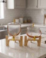 Ribbed glass beverage dispenser with leather carrying handle and gold spigot set on a wooden stand