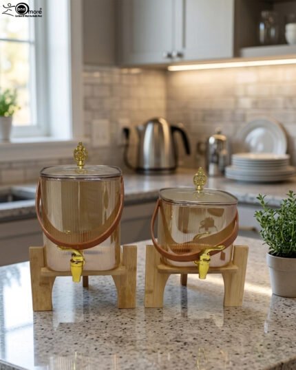 Two amber-shaded glass beverage dispensers with gold spigots, leather handles, and wooden stands on a kitchen counter.