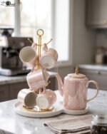 Luxury iridescent ceramic tea set with 6 cups, kettle, white ceramic tray, and golden display stand on a kitchen counter.
