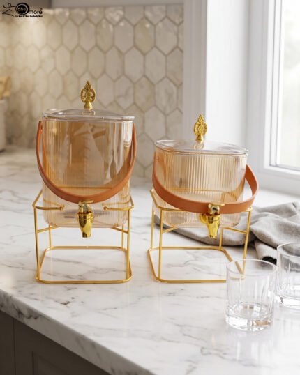 Amber shaded ribbed glass beverage dispenser with gold spigot, leather handle, and gold metal stand on a marble countertop