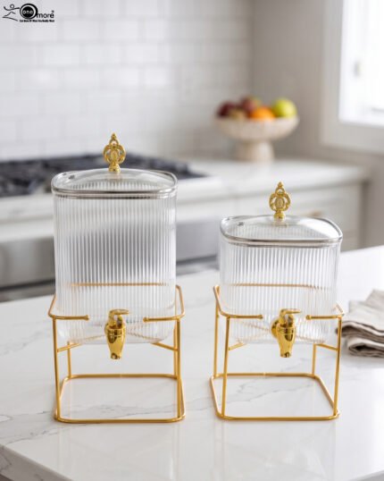 Two ribbed glass beverage dispensers with gold spigots and metal stands on a kitchen counter