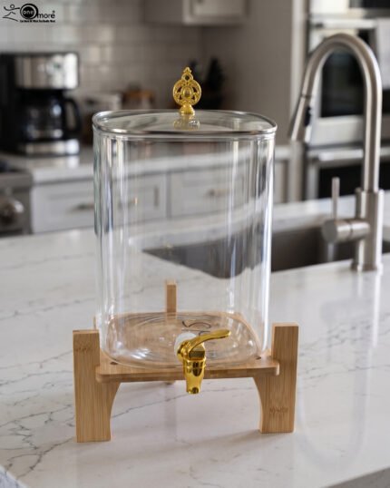 Clear 9.5L glass beverage dispenser with gold spigot on a wooden stand on a white marble countertop