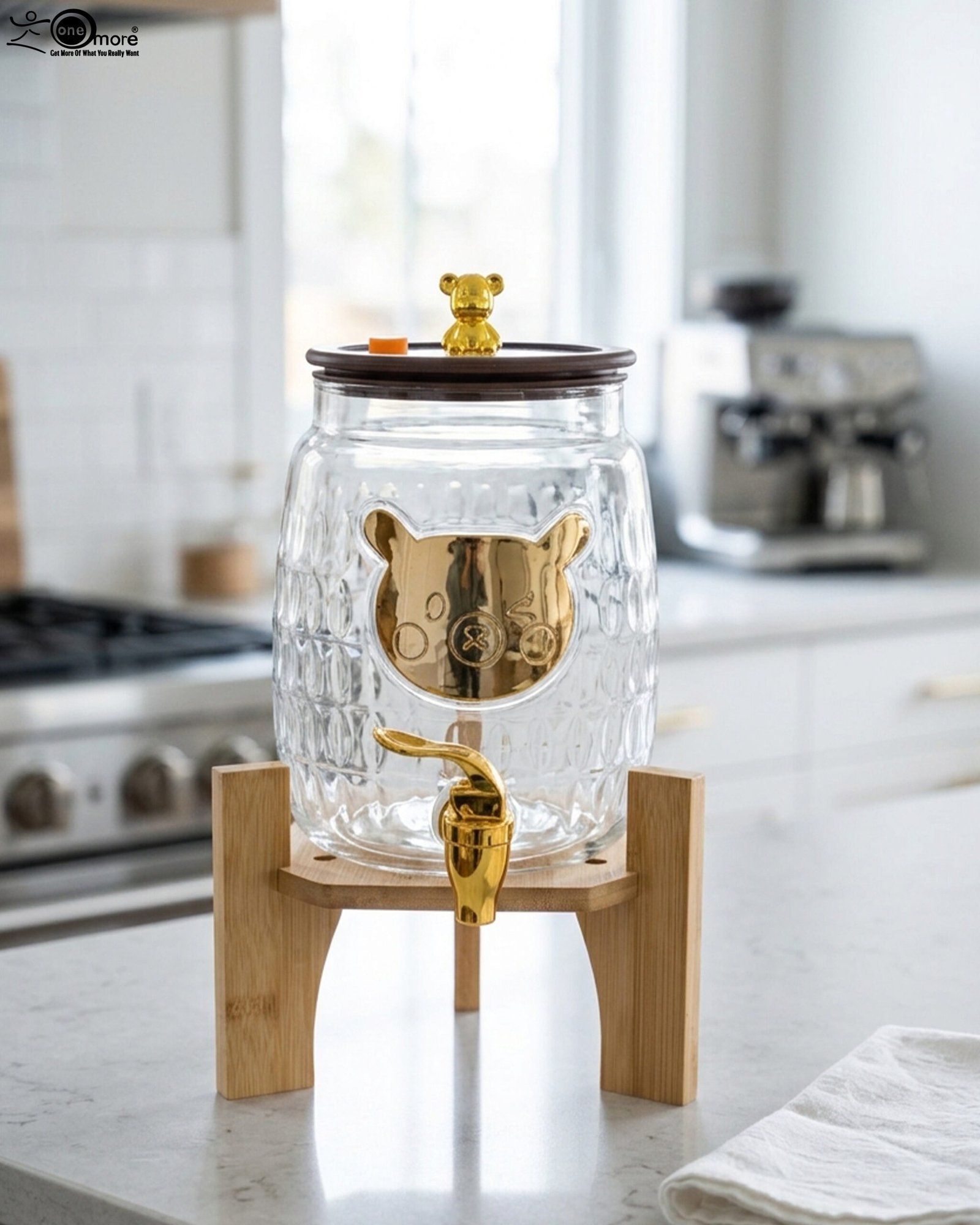 1 3.6-liter clear glass drink dispenser featuring a gold bear face design, gold spigot, and sturdy wooden stand set on a kitchen counter