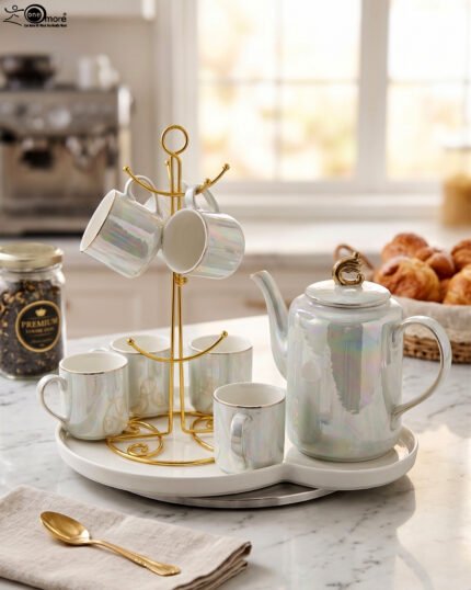 Luxurious iridescent ceramic tea set featuring six cups, one kettle, and a gold-finish stand on a white tray, arranged on a marble kitchen counter.