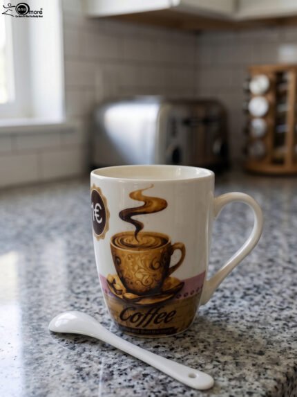 White ceramic coffee mug with vintage coffee cup graphic next to a matching white spoon on a countertop.