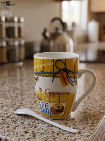 Printed ceramic coffee mug with vintage yellow wooden pattern, cappuccino text, coffee bean prints, and matching white spoon on a kitchen counter