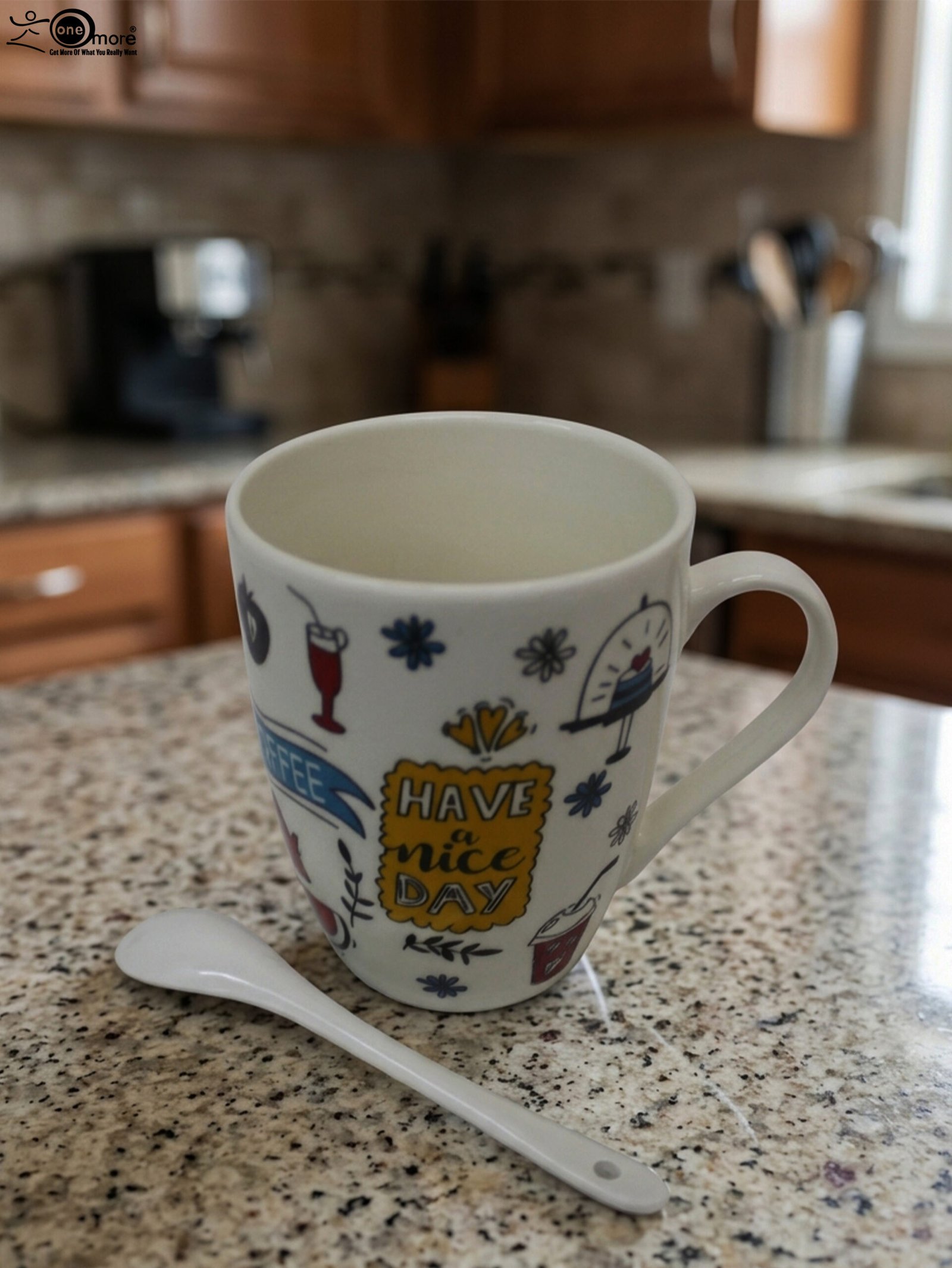 1 White ceramic coffee mug printed with 'Have a Nice Day' doodle art next to a matching ceramic spoon on a kitchen counter.