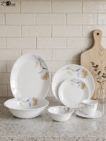 Elegant 32-piece white floral printed dinner set displayed on a marble countertop with plates, bowls, cups, and a platter