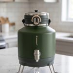 Bangda 5L matte green insulated water cooler jug with stainless steel dispenser tap and metal folding stand on a white marble countertop.
