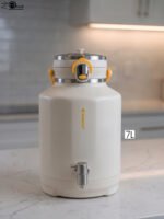 Off-white 7-liter insulated water cooler dispenser with spigot tap and stainless steel lid on a kitchen counter
