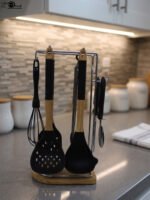 8 piece black silicone kitchen utensil set with wooden handles hanging on a chrome stand