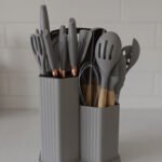 Grey 19-piece silicone kitchen utensil and knife set with wooden handles in a matching grey dual-compartment storage block.