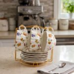 Luxury ceramic tea set with 6 floral cups, matching saucers, and a golden stand on a kitchen counter.