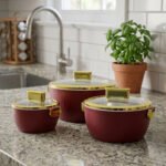 3-piece luxury insulated hotpot set in ribbed maroon with gold rims and clear glass lids on a granite kitchen countertop.
