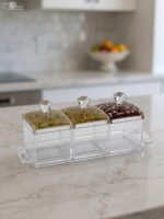 3-piece clear acrylic spice and dry fruit jar set with patterned lids, crystal knobs, and clear tray on marble kitchen counter