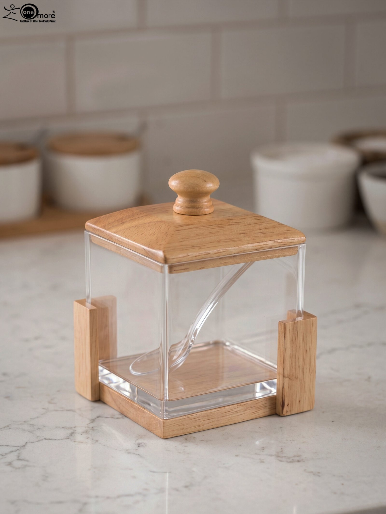 1 Square clear acrylic sugar pot with a natural wooden lid, clear serving spoon, and wooden base stand on a kitchen countertop.