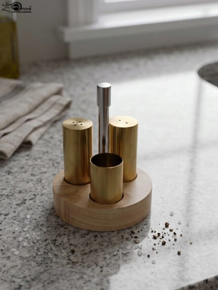 Brushed brass metal salt and pepper shakers with toothpick holder set in a round wooden base on a granite countertop