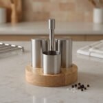 Stainless steel salt and pepper shakers with toothpick holder set in a wooden base on a marble kitchen countertop
