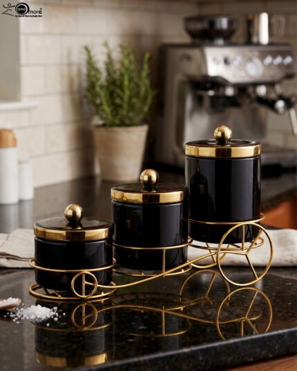 Luxury 3-piece black and gold ceramic storage jar set with golden lids arranged on an elegant gold metal cart stand on a modern kitchen countertop.