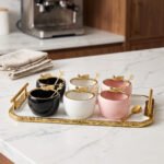 Luxury ceramic ice cream set with six multi-colored bowls and a gold-trimmed serving tray on a white marble kitchen counter