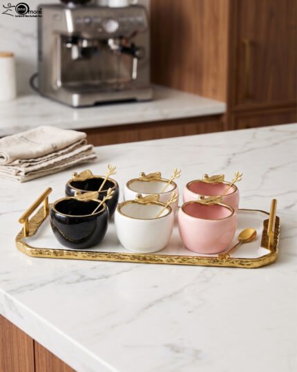 Luxury ceramic ice cream set with six multi-colored bowls and a gold-trimmed serving tray on a white marble kitchen counter