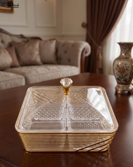 Two luxury clear acrylic dry fruit serving dishes with gold trim, crystal knobs, and partitioned compartments displayed on a modern wooden coffee table.