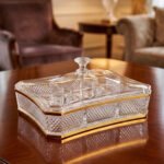 Elegant rectangular crystal dry fruit dish with multiple compartments, gold trim, and a matching lid placed on a wooden table.