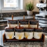 Luxury ceramic kitchen jar set with golden tree and deer patterns, wooden lids with loop handles, and a matching wooden display stand on a kitchen countertop.