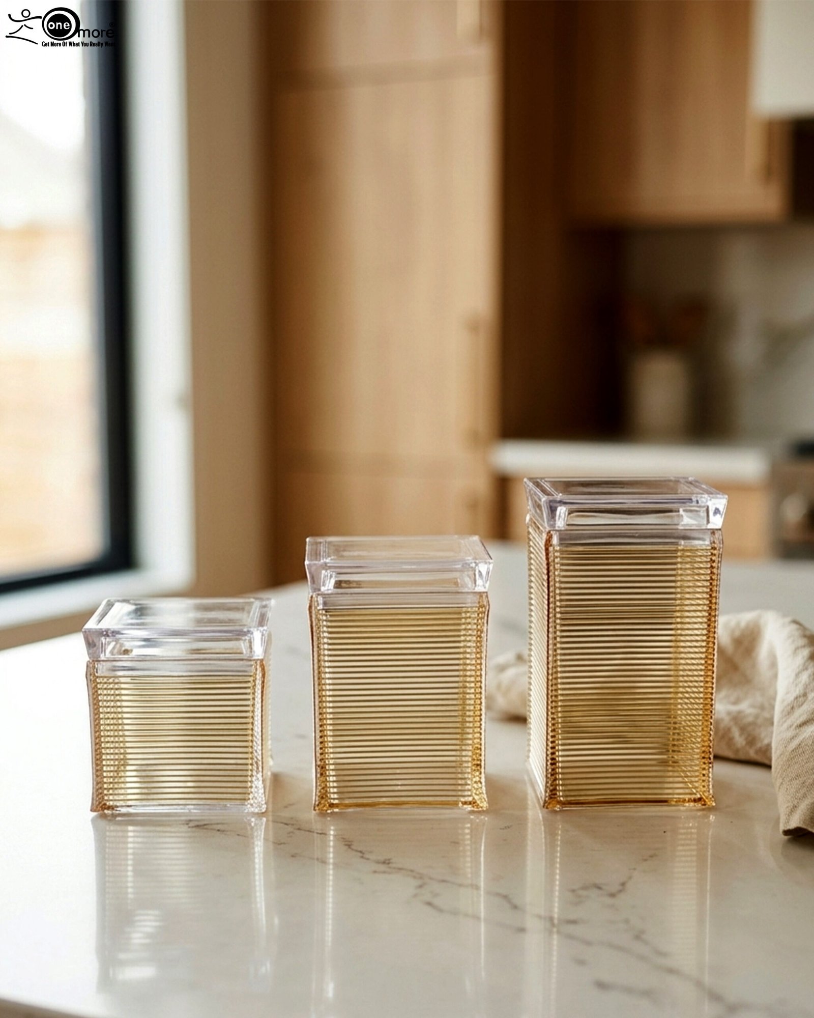 1 Three varying heights of clear ribbed acrylic storage jars with lids arranged on a modern kitchen countertop.