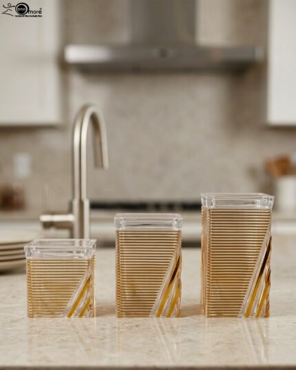 A set of three clear acrylic storage jars with decorative ribbed gold detailing, displayed neatly on a modern kitchen countertop.