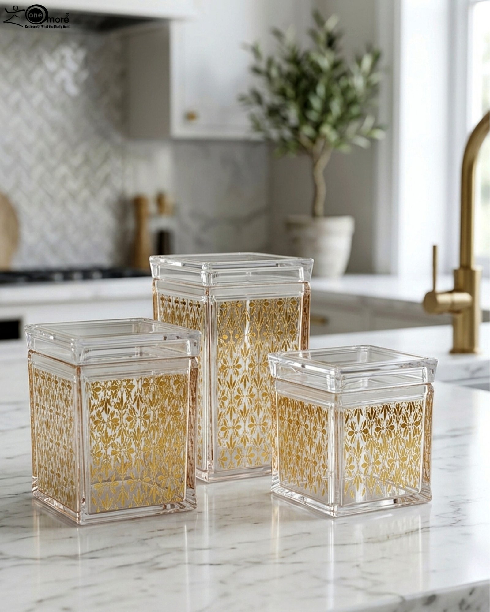 1 Set of three clear acrylic kitchen storage jars with elegant gold patterned designs, displayed on a marble countertop.