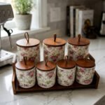 Floral ceramic kitchen canister and jar set with wooden lids and display stand on a kitchen counter
