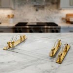 Luxurious clear acrylic serving tray set with polished gold handles and curved design, displayed on a marble countertop in a modern kitchen