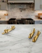 Luxurious clear acrylic serving tray set with polished gold handles and curved design, displayed on a marble countertop in a modern kitchen