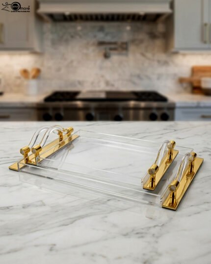 Luxurious clear acrylic serving tray set with polished gold handles and curved design, displayed on a marble countertop in a modern kitchen