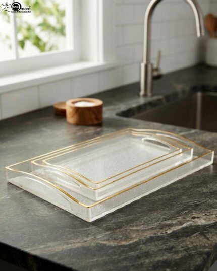 Nesting clear acrylic serving tray set with elegant gold trim and built-in handles, displayed on a modern kitchen countertop.