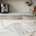 Clear acrylic tray set with textured glass look, gold accents, and transparent handles displayed on a white marble countertop.