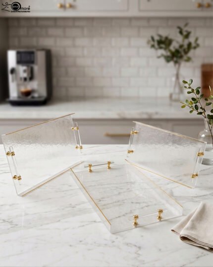 Clear acrylic tray set with textured glass look, gold accents, and transparent handles displayed on a white marble countertop.