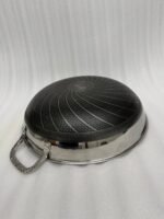 Stainless steel non-stick cookware set featuring 30cm and 32cm pans with glass lids displayed on a wooden countertop in a modern kitchen.
