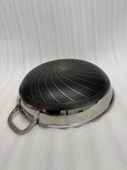 Stainless steel non-stick cookware set featuring 30cm and 32cm pans with glass lids displayed on a wooden countertop in a modern kitchen.