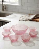 7-piece grey glass fruit set featuring one large serving bowl and six matching small bowls with gold rims, displayed on a kitchen countertop.