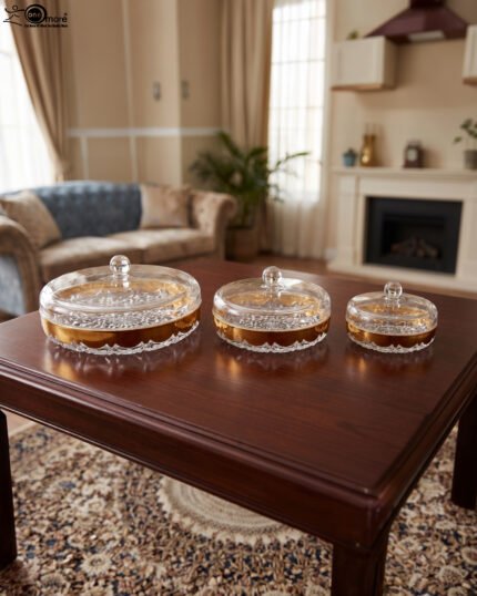 Three luxury crystal dry fruit dishes with gold rims and lids in Small, Medium, and Large sizes displayed on a dark wooden coffee table.