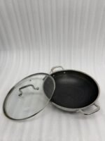 Stainless steel non-stick cookware set featuring 30cm and 32cm pans with glass lids displayed on a wooden countertop in a modern kitchen.