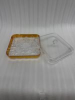 Two square crystal dry fruit dishes with gold trim bases and glass lids displayed on a wooden table in a luxury living room setting.