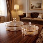 Two elegant crystal dry fruit dishes with lids and gold trim displayed on a wooden table in a luxury living room setting, available in medium and large sizes.