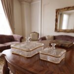 Two square crystal dry fruit dishes with textured patterns and gold trim, displayed in medium and large sizes on a wooden table.